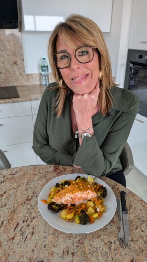Céline souriante devant une assiette équilibrée avec légumes, protéines et féculents, illustrant une alimentation saine et consciente.