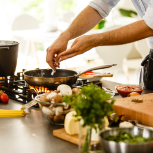 Bras d’une personne ajoutant des aliments dans une casserole pour réchauffer un plat de batch cooking